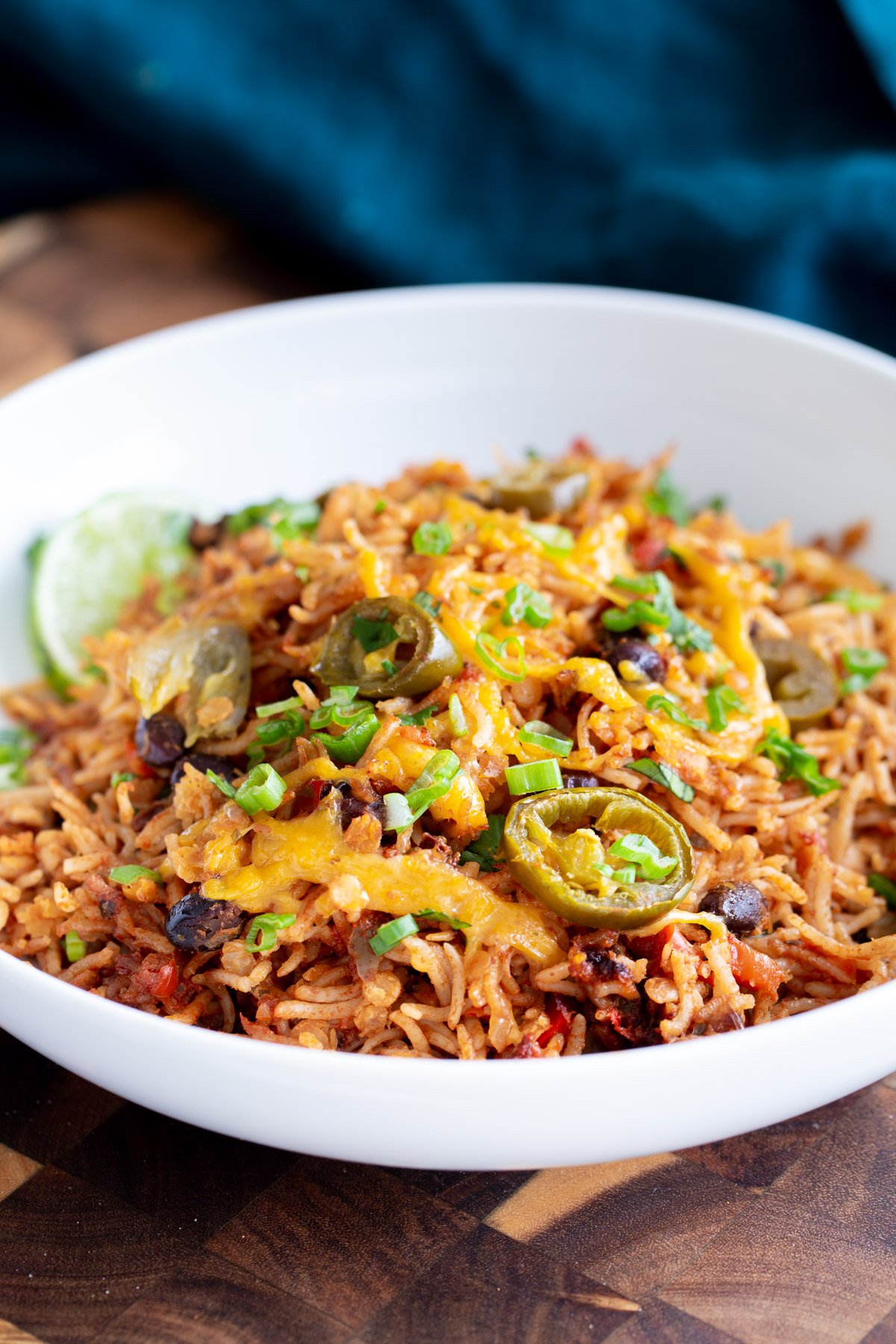 a plate with tex mex rice casserole topped with green onions and pickled jalapenos