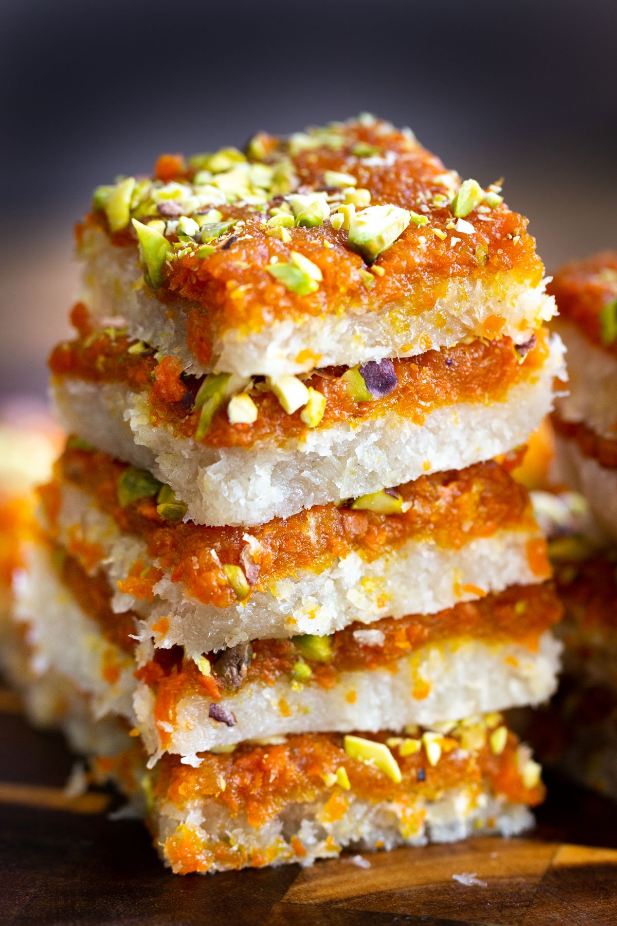 stacked carrot halwa coconut burfi bars on a wooden board