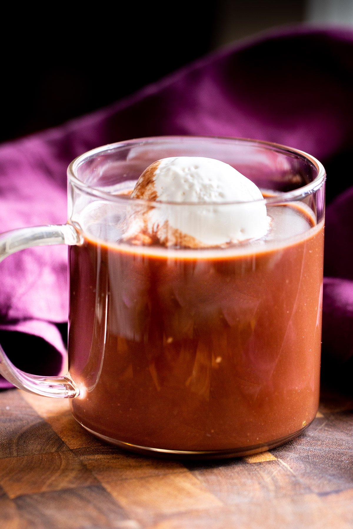 a glass with vegan hot chocolate topped with coconut cream