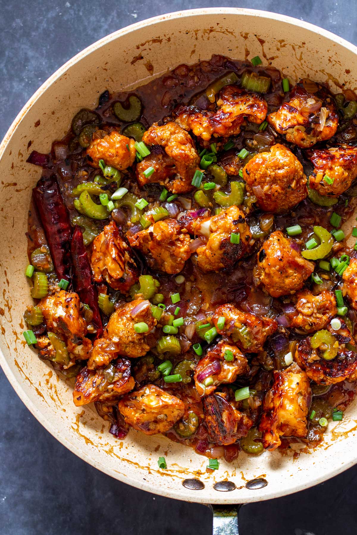 vegan black pepper cauliflower being tossed with sweet and spicy sauce in a saucepan
