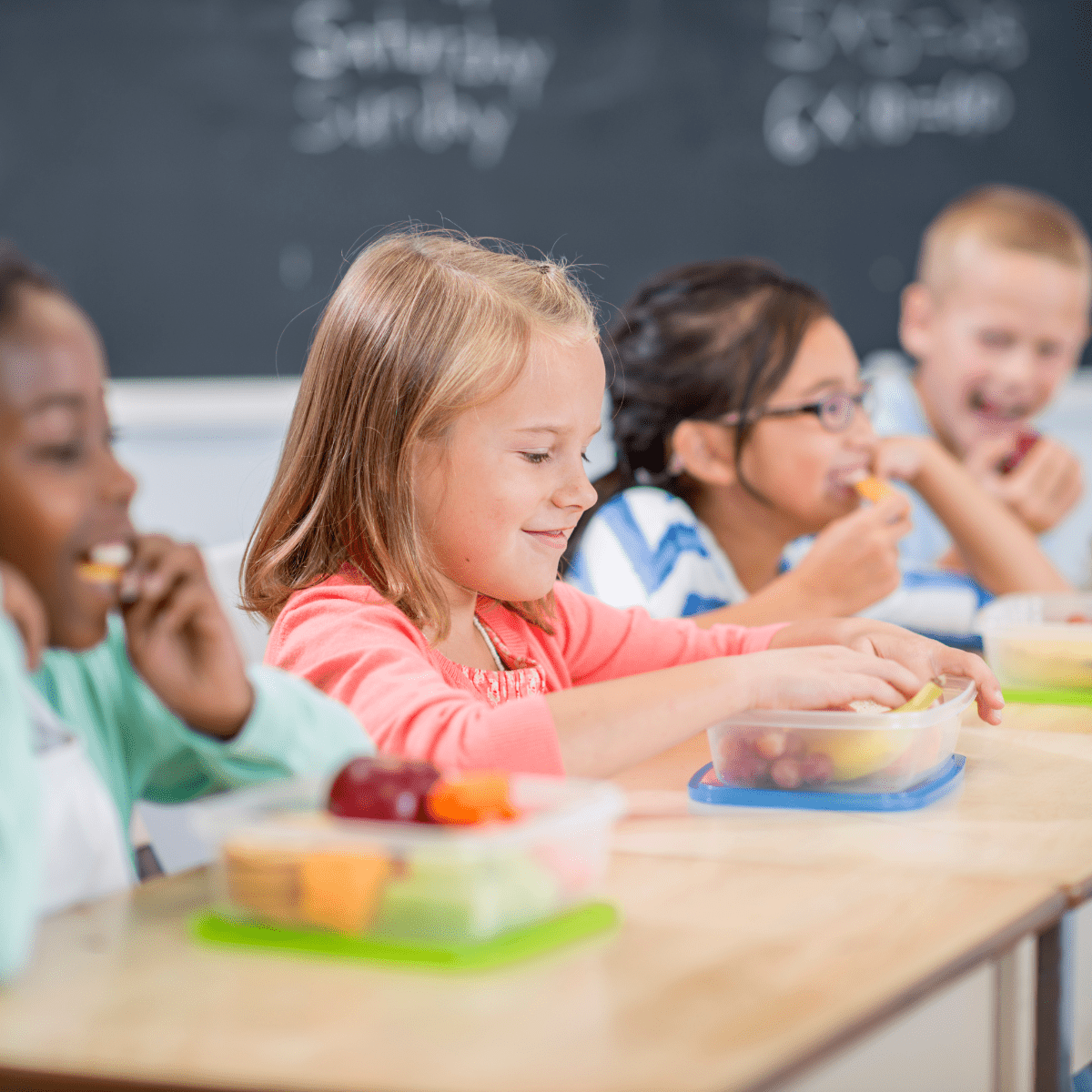 Four children eating snacks at their school desks