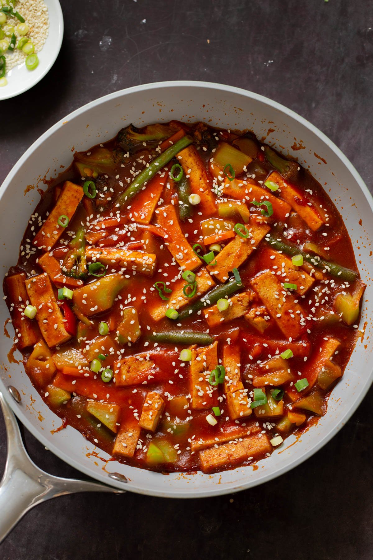 gochujang tofu stir fry in a pan topped with sesame seeds and green onion