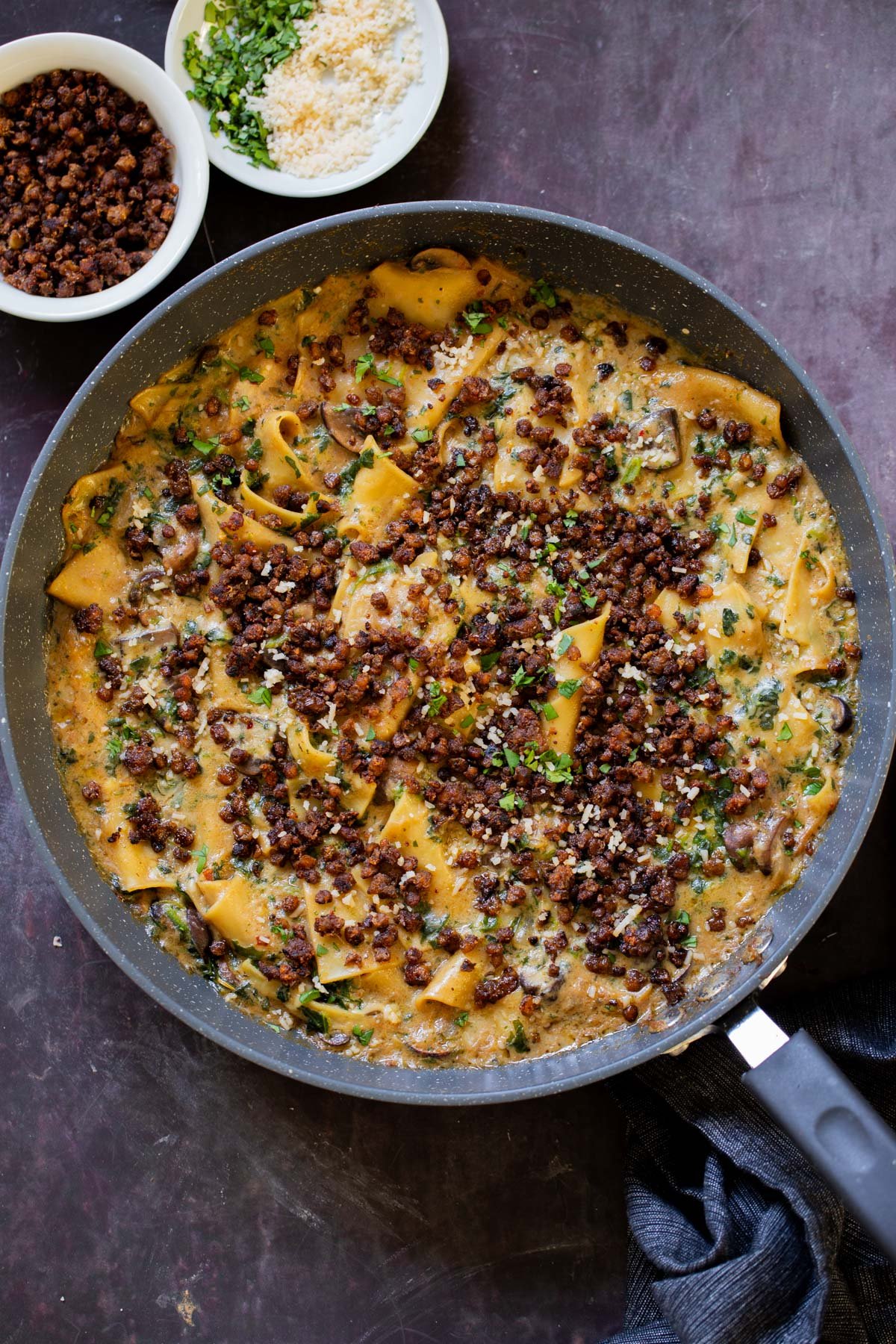 smoky skillet lasagna in the pan, topped with crispy lentils and fresh herbs