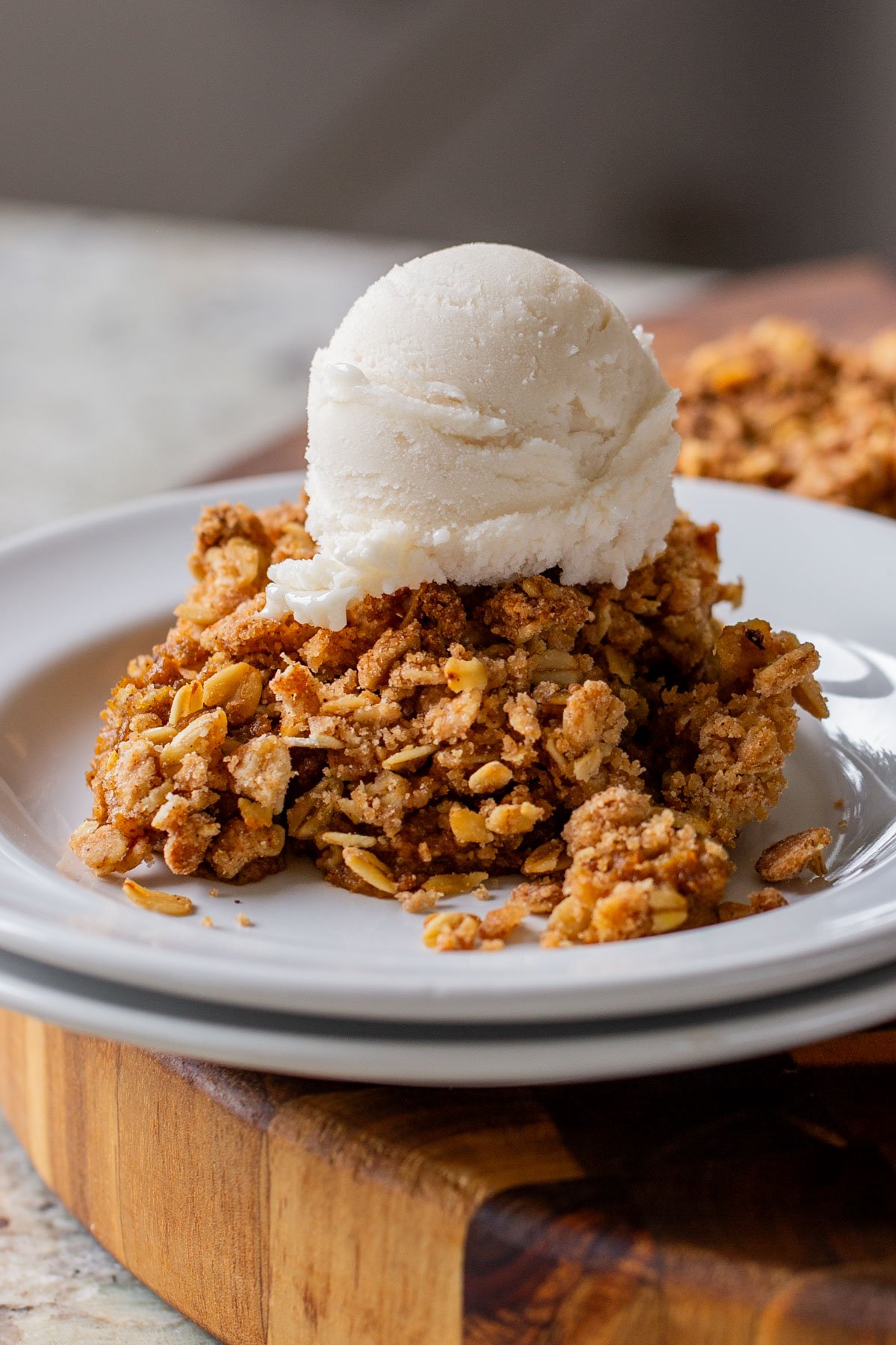 slice of pumpkin crisp on a white plate with ice cream on top