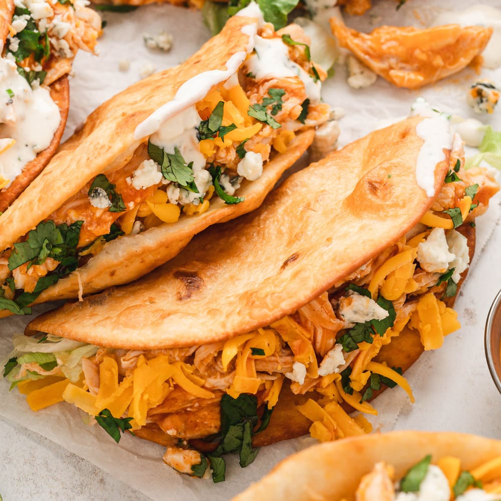 2 Buffalo chicken tacos laying on top of each other.